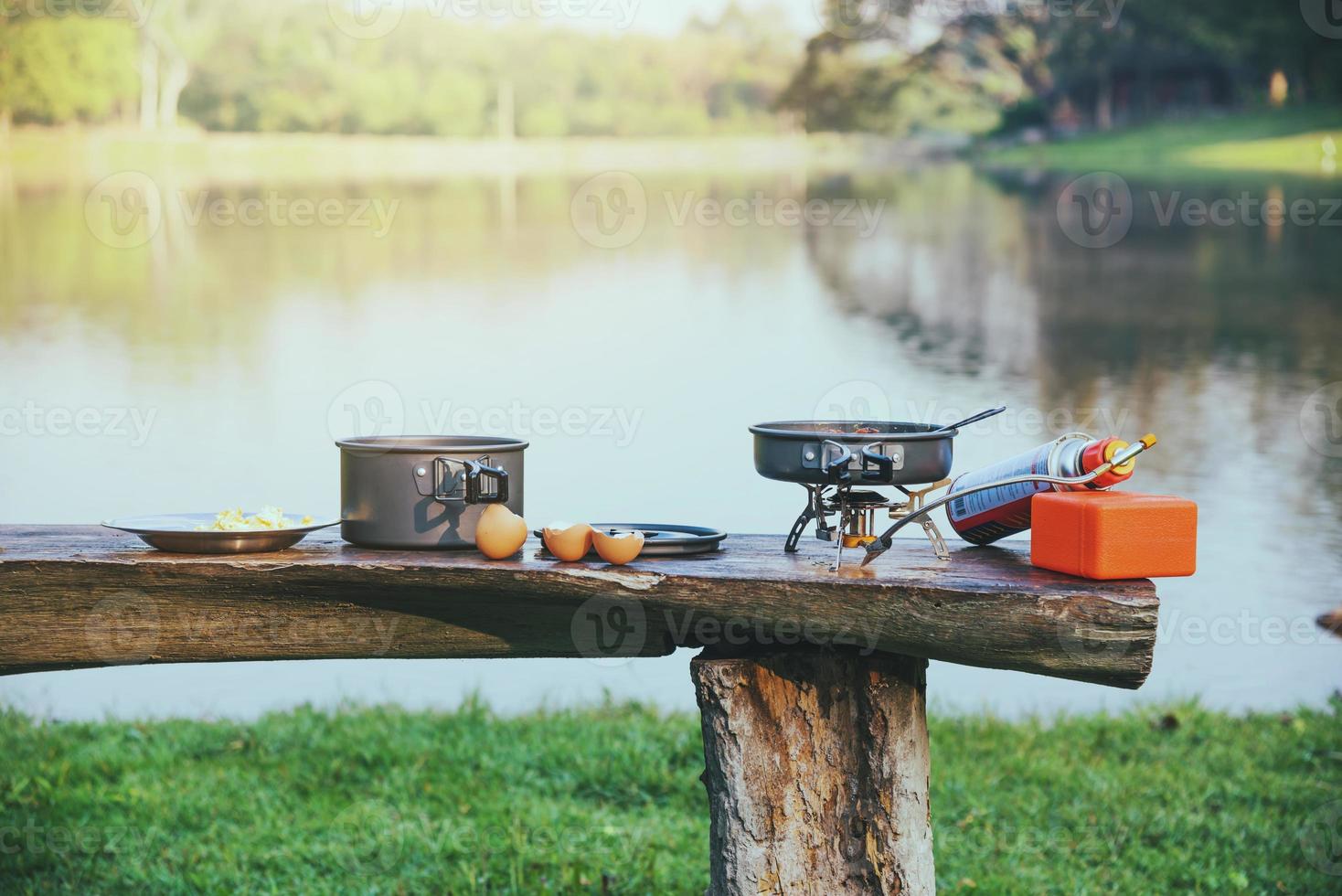 bakgrunden av grytan och gas picknick som är placerad på bordet i trä. camping, picknick, matlagning, äta vid sjön. foto