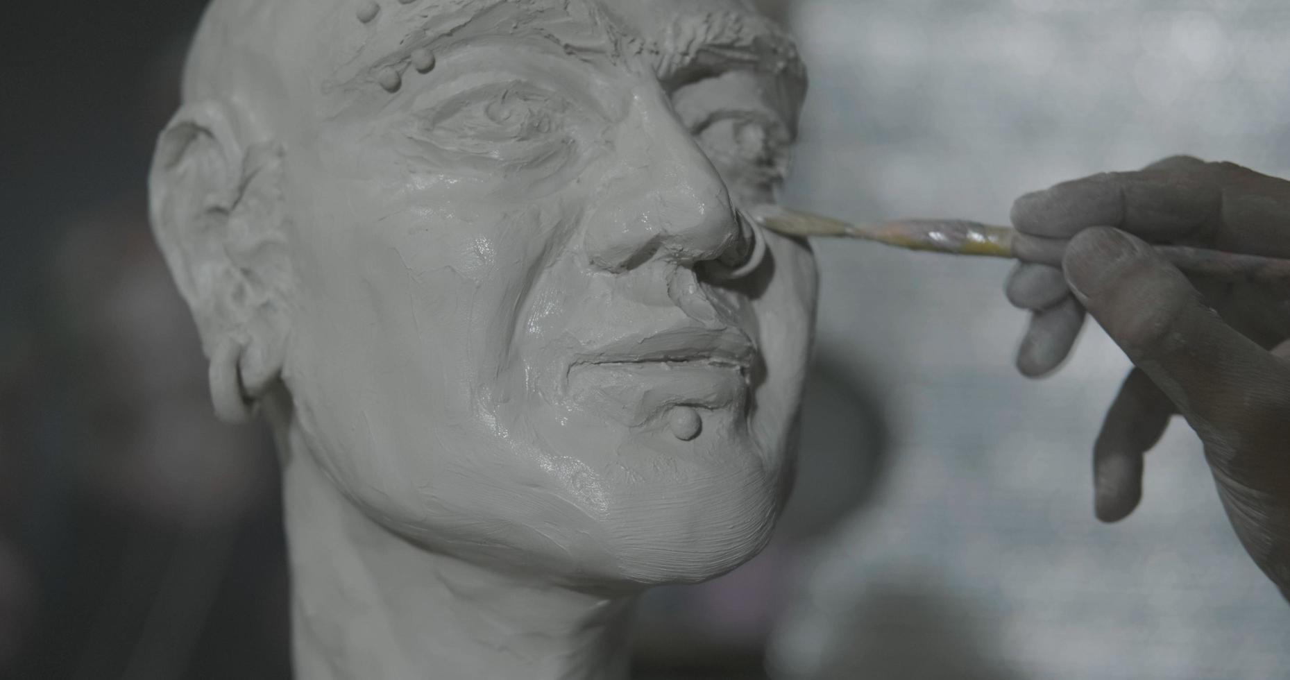 skulptör arbete med lera porträtt av kvinna i mörk studio uhd4k foto