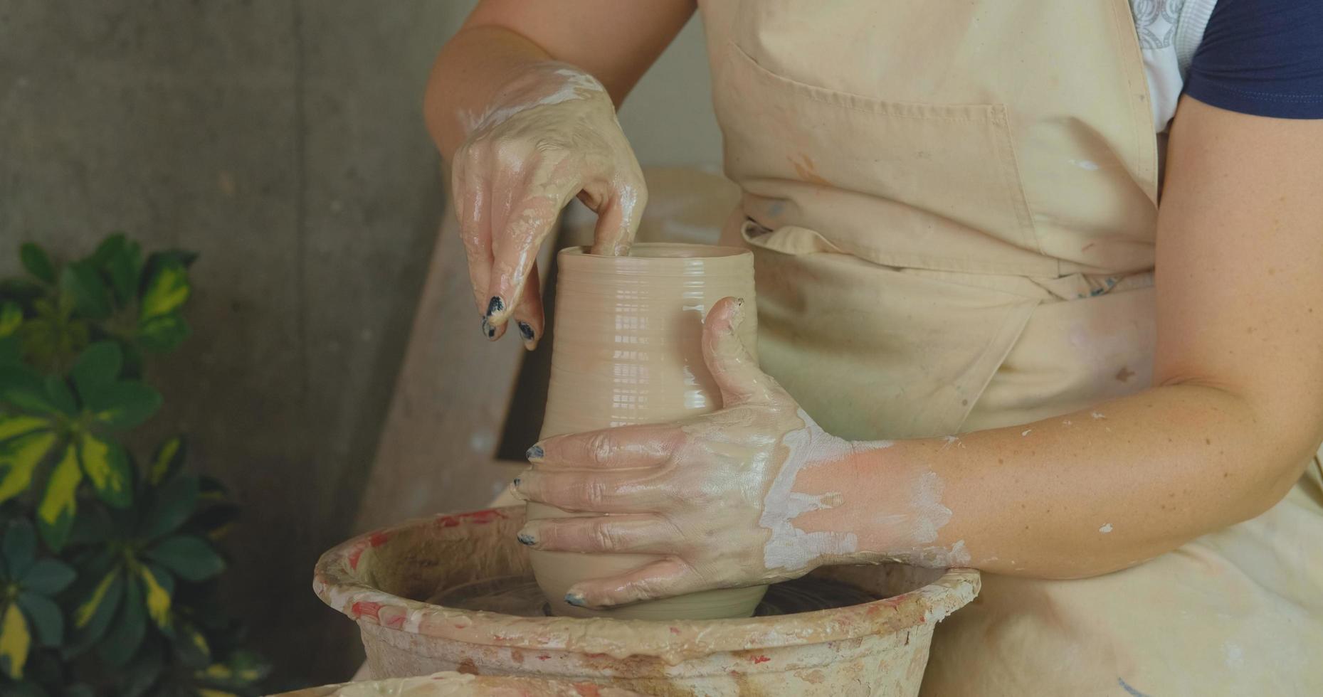 närbild av kvinnans handarbete med lera i keramikstudio foto