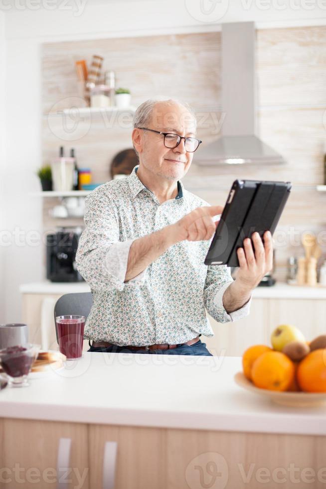 glad gammal man håller tablet pc foto
