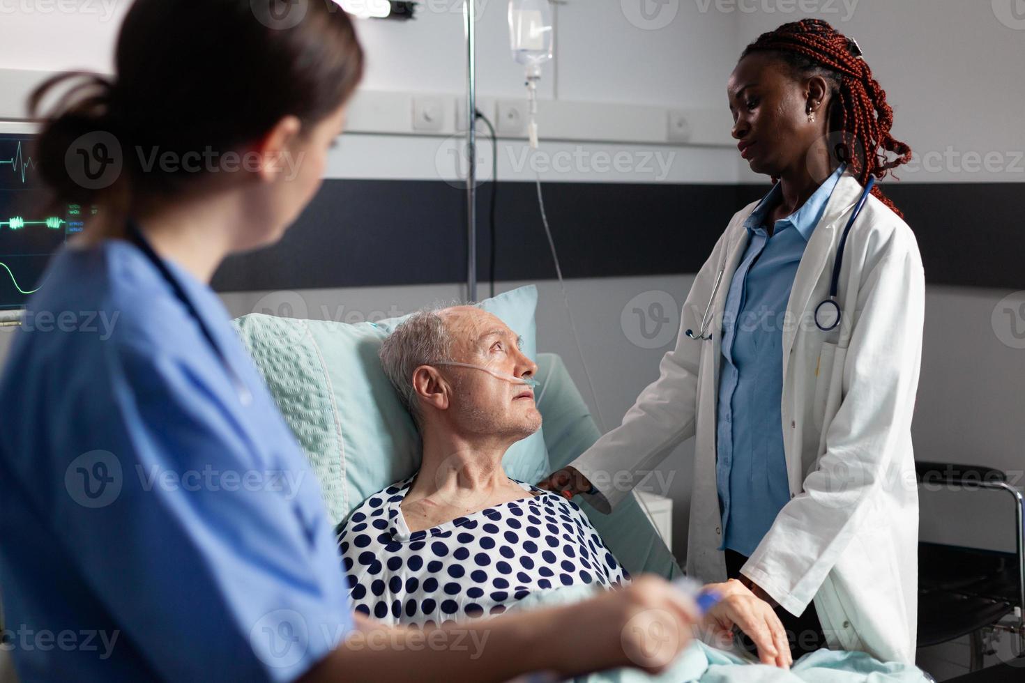 afrikansk läkare i sjukhusrummet diskuterar med sjuk senior man foto