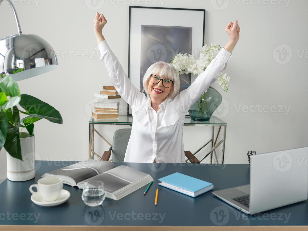 senior vacker grått hår kvinna i vit blus glad på kontoret. arbete, seniorer, problem, framgång, hitta en lösning, erfarenhetskoncept foto