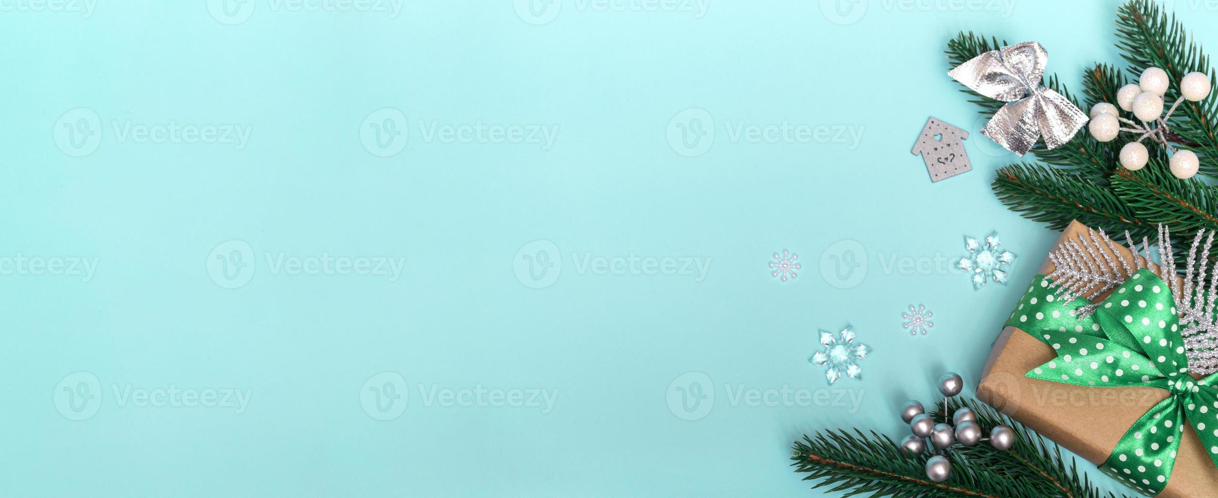 god Jul och Gott Nytt År. platt lägga av en gåva med ett grönt prickigt band och ornament på en blå bakgrund. julkort kopia utrymme närbild foto