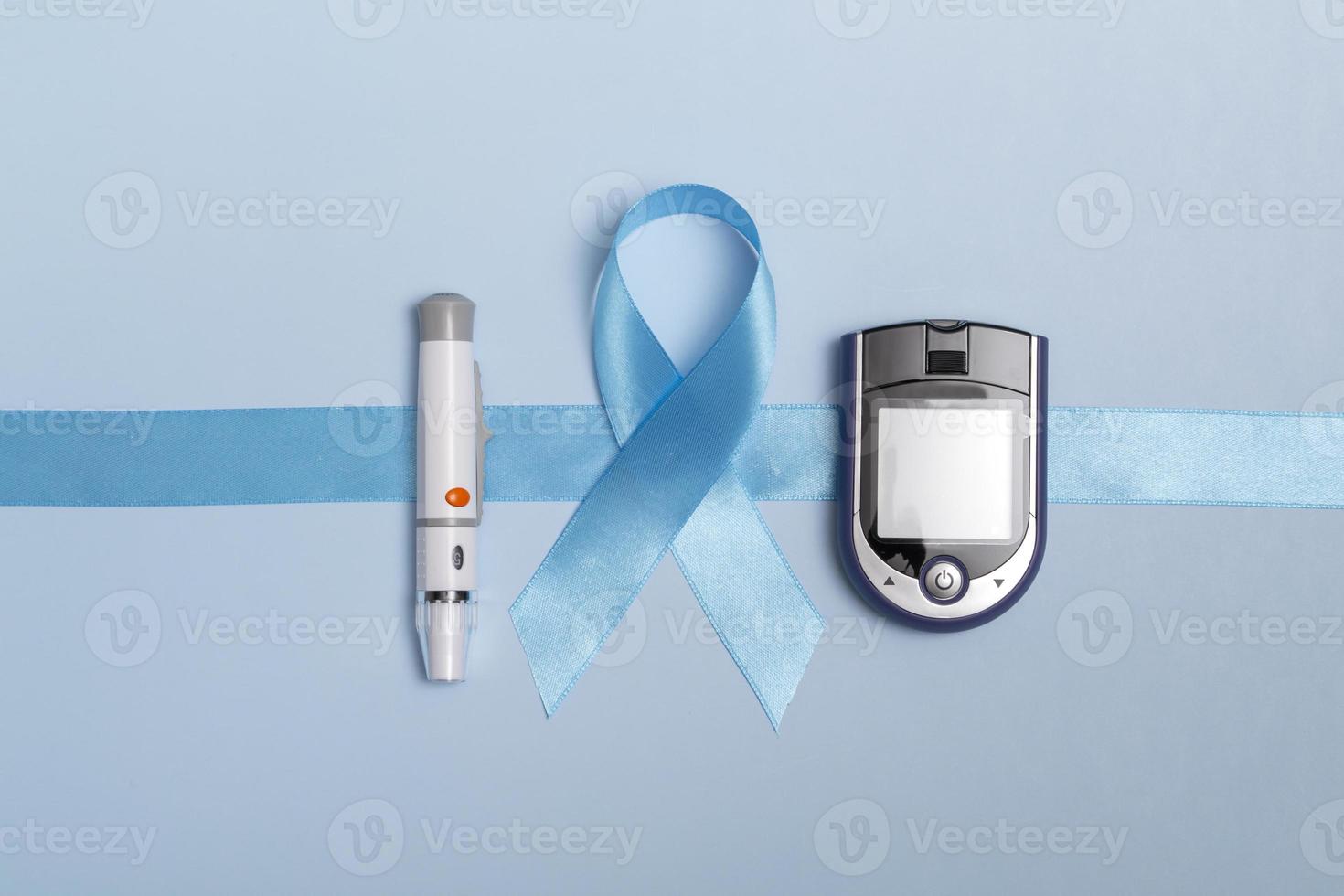 närbild ovanifrån av konceptet för världsdiabetesdagen 14 november. blå tejp med bloddroppar och en glukosmätare på blå bakgrund. kopieringsutrymme foto
