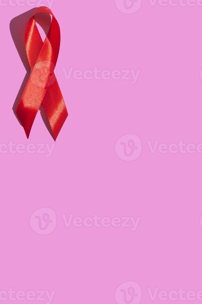 internationella aidsdagen. rött band med en hård skugga på en rosa bakgrund. hjälpmedel medvetenhet koncept. vertikal foto