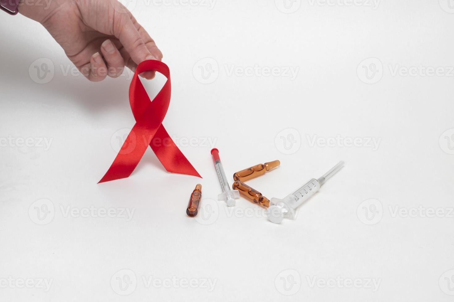 medicinskt koncept för World Aids Day i december. rött aids medvetenhet band fast i en kvinnas hand på en vit bakgrund. närbild foto