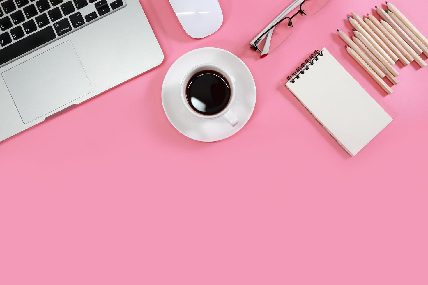 platt liggande arbetsbord med bärbar dator, kontorsmaterial, kaffekopp, mobiltelefon, surfplatta och kaffekopp på rosa bakgrund foto