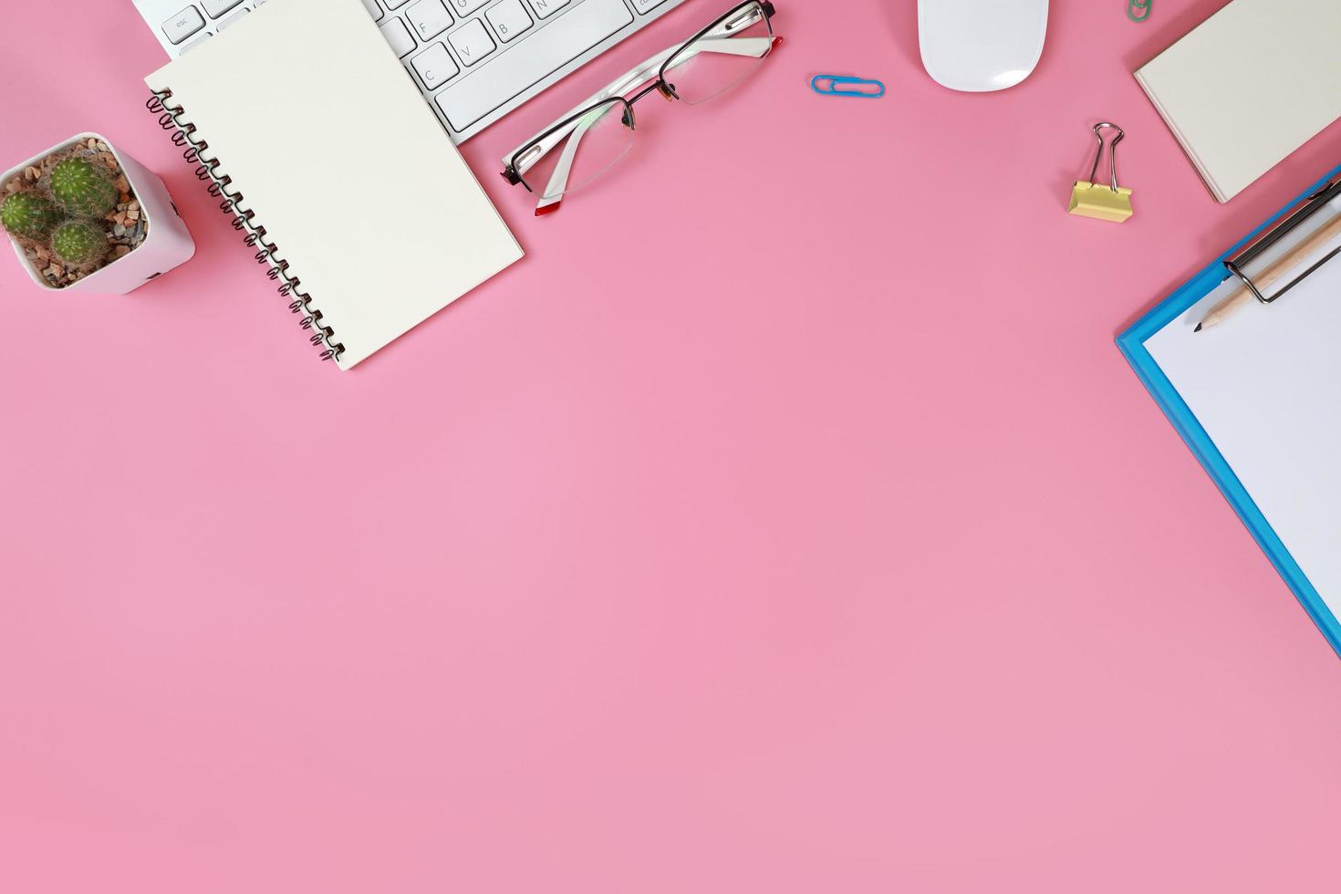 platt liggande arbetsbord med bärbar dator, kontorsmaterial, kaffekopp, mobiltelefon och kaffekopp på rosa bakgrund foto