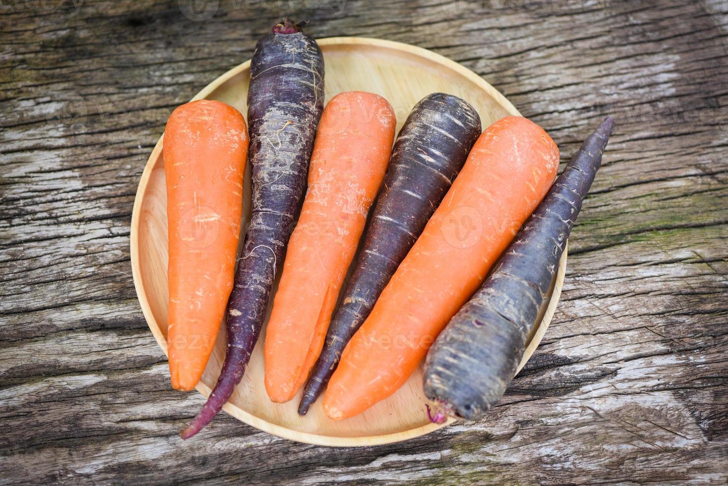 morot och lila morot på bricka, färsk morot för matlagning vegetarisk på träbord i köket. foto