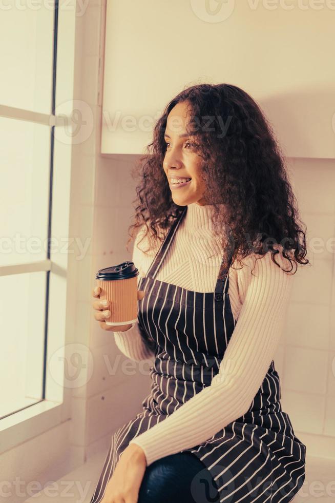latinsk kvinna dricker kaffe i köket foto