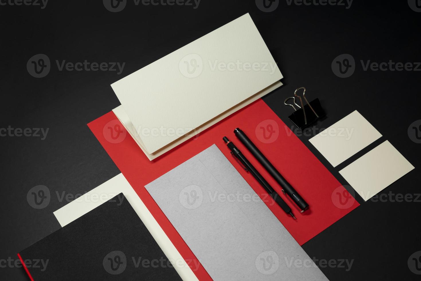 brevpapper branding mockup mall med rött A4 brevhuvud, visitkort, kuvert, anteckningsbokpenna. mörk bakgrund riktig fotografering foto