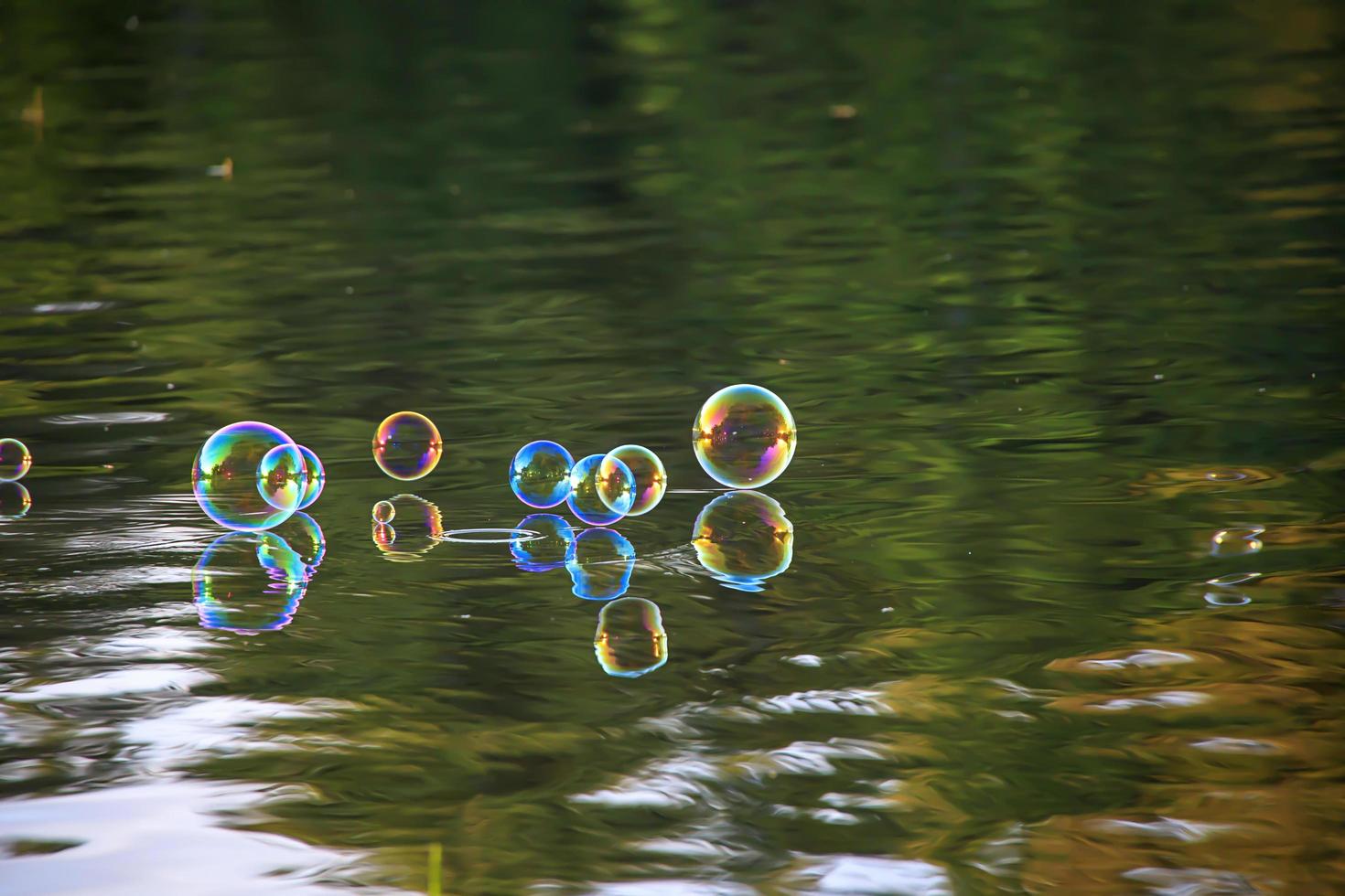 färgglada bubblor flyter på toppen av en damm foto