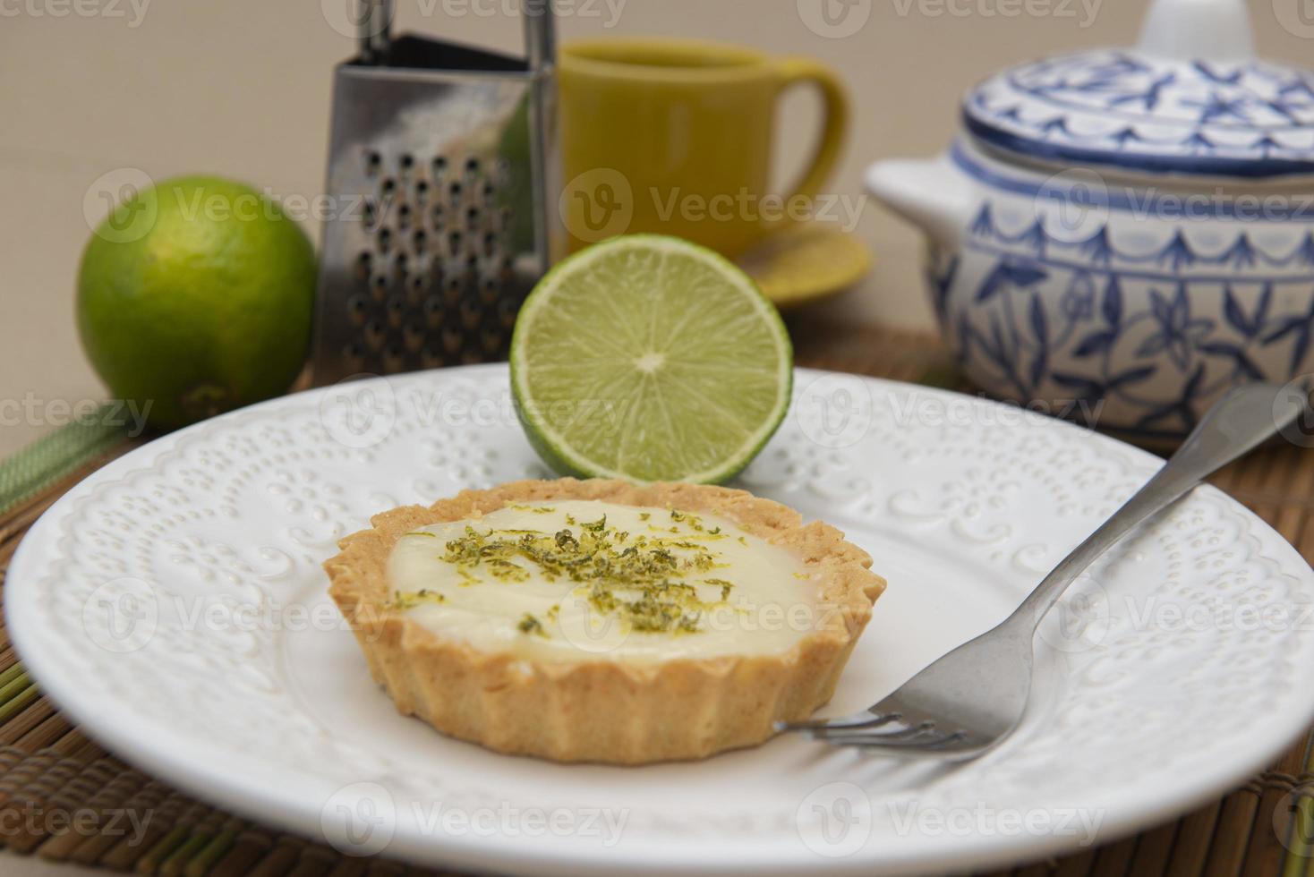 sidovy av citrontårta på tallriken med citronskivor på bordet. foto