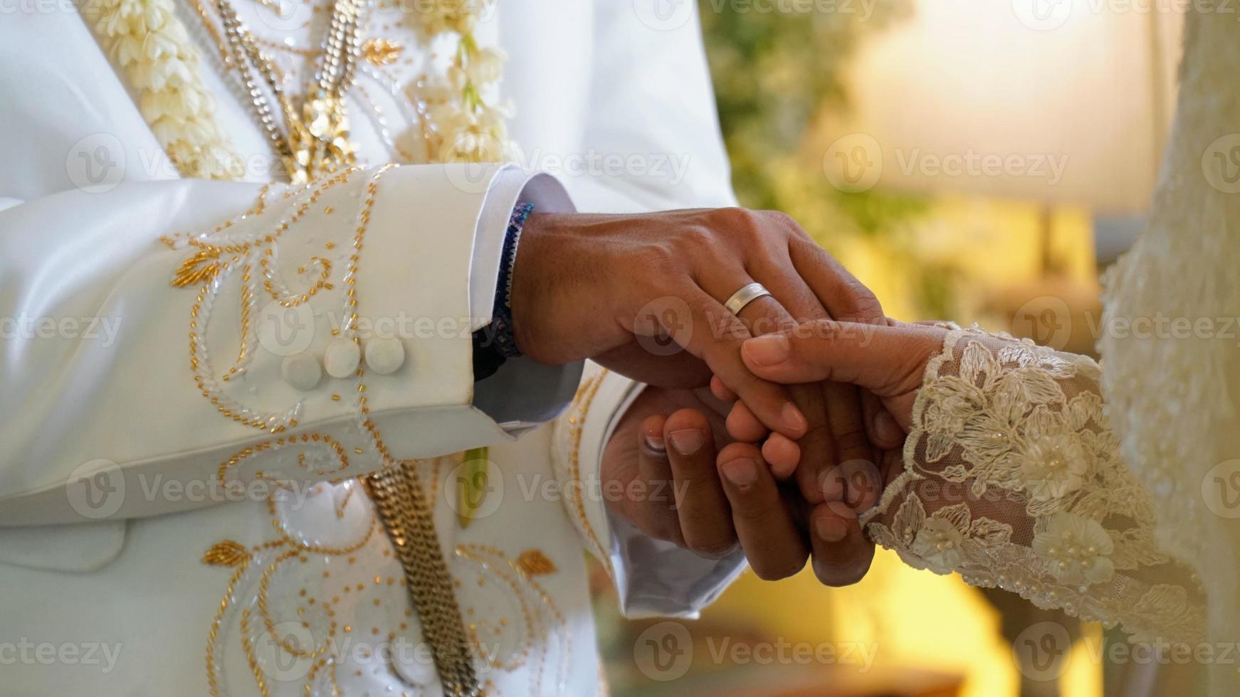 närbild av handskakning av brudgum och brud i indonesiskt bröllop. foto