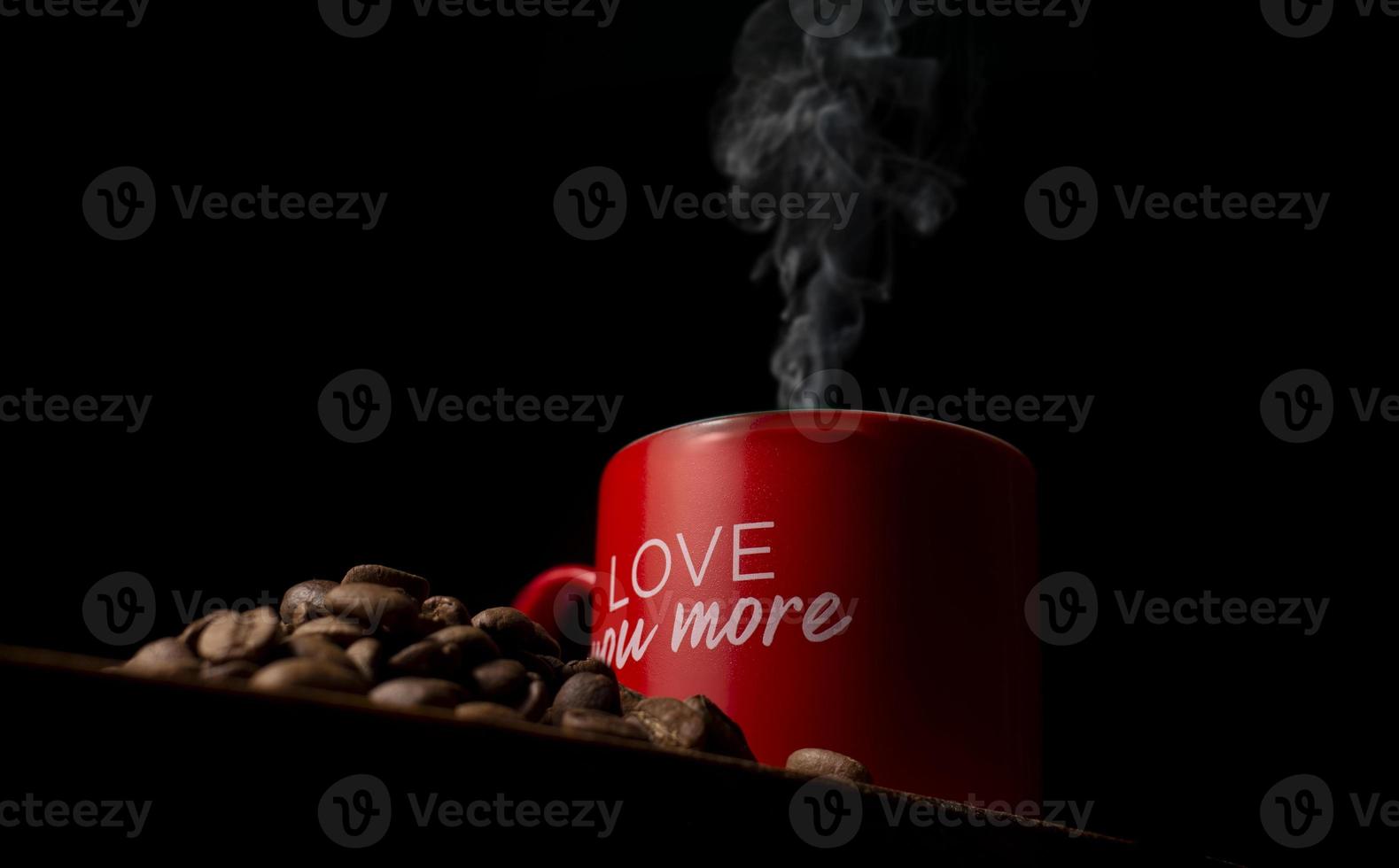 röd kaffekopp på träbord, kaffekorn, svart bakgrund foto
