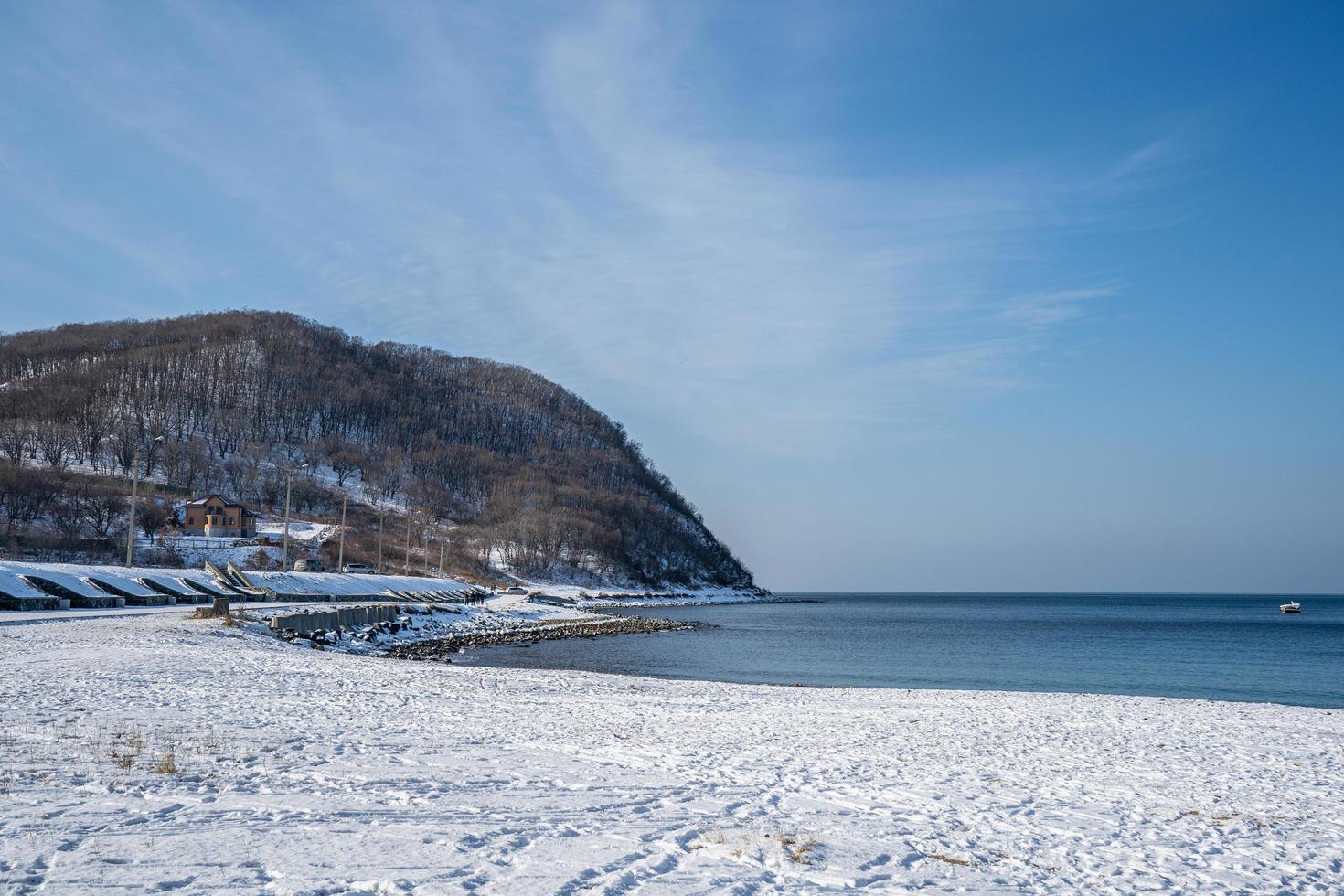 havslandskap med en snötäckt strand på en stenbakgrund. foto