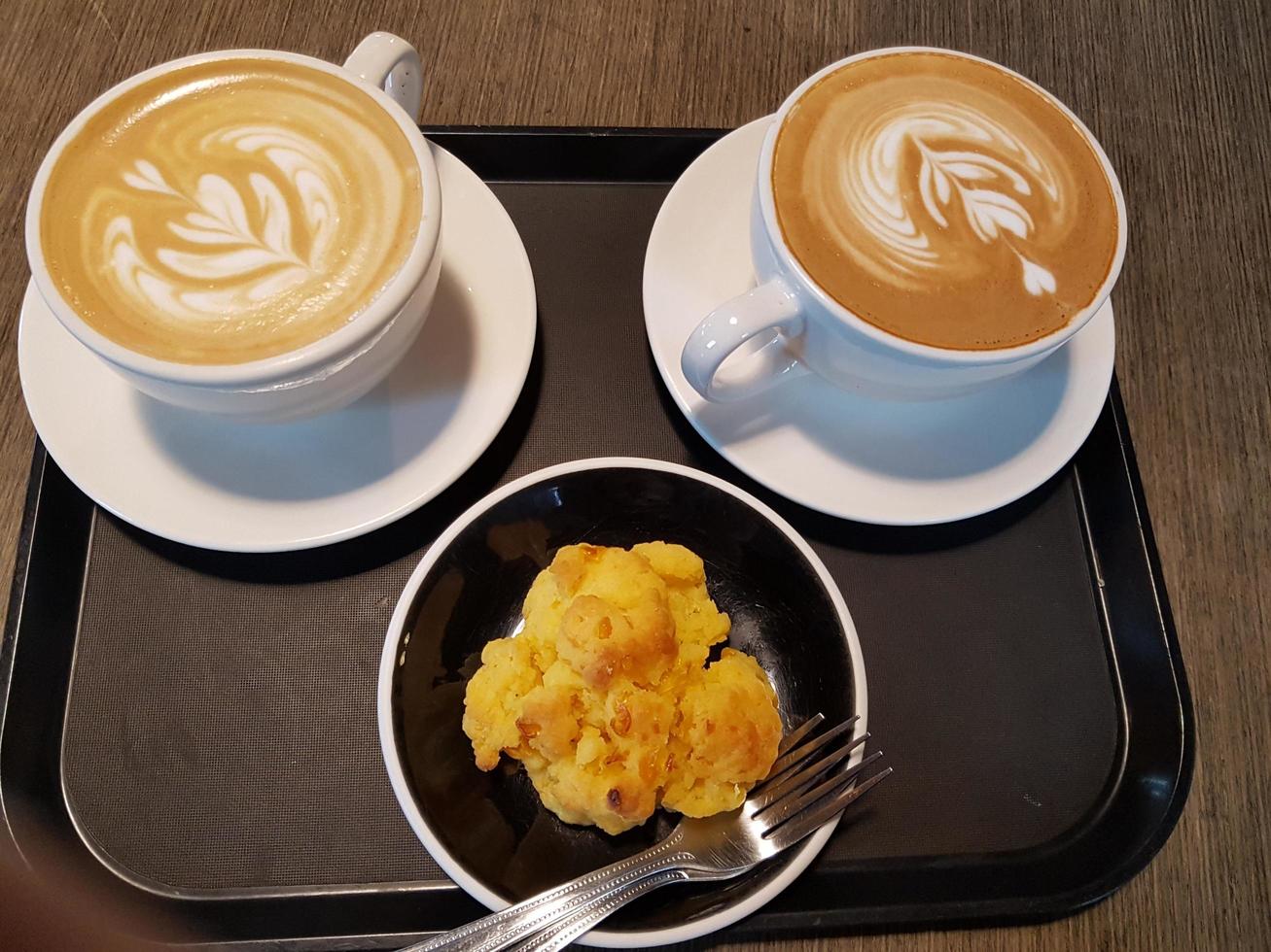 två mjölkkaffe med unik form på kryddan och snacks på tallriken foto