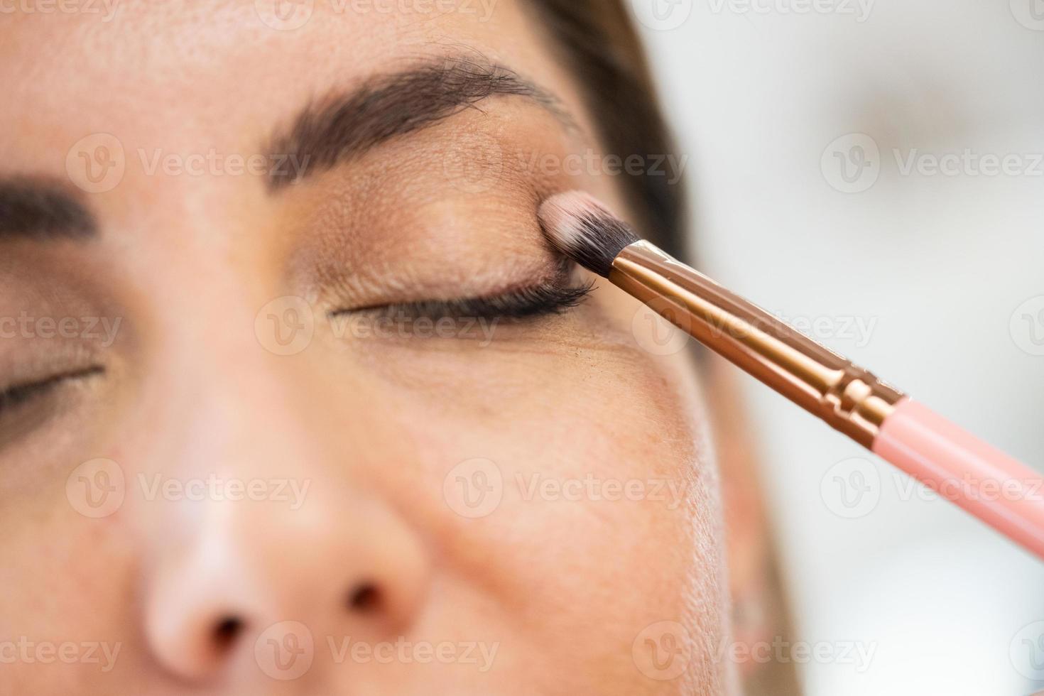 närbild av en makeupartist som applicerar ögonskugga på sin klient. foto