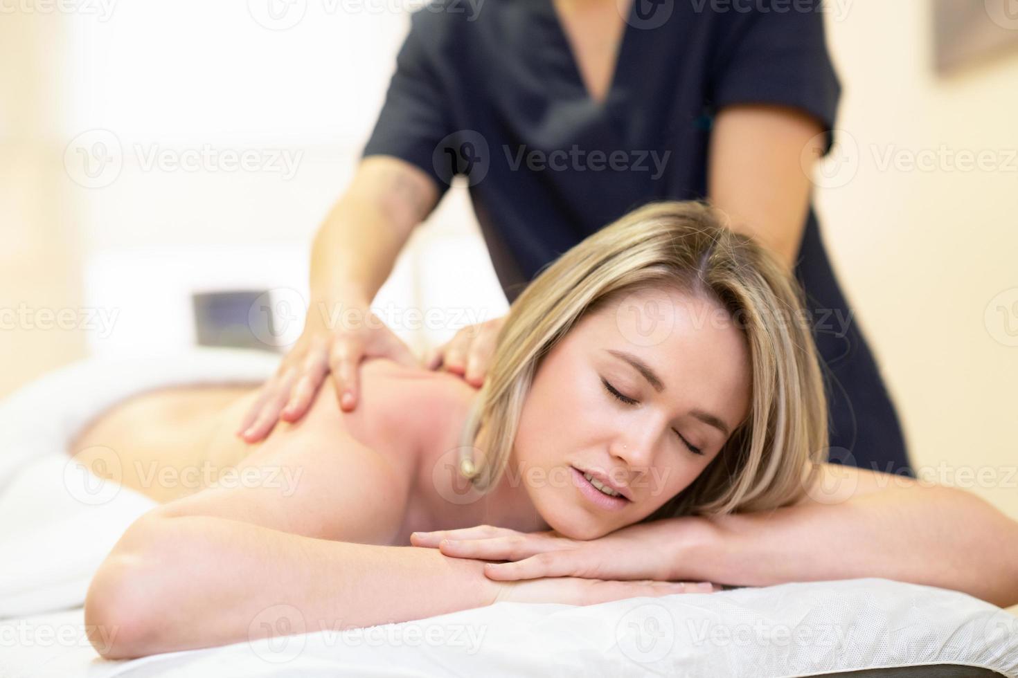 kvinna liggande på en bår som får en ryggmassage. foto