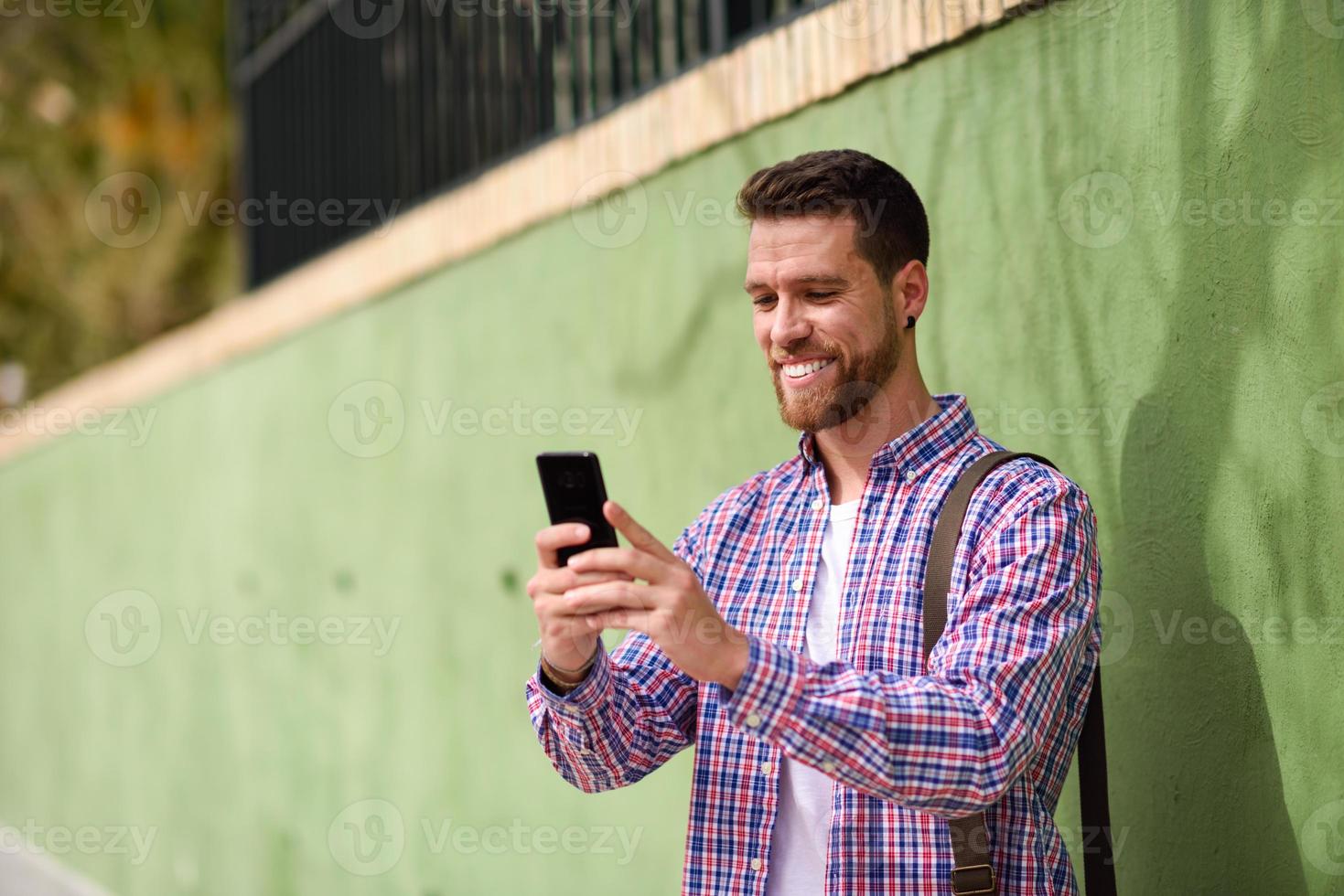ung man tittar på sin smarta telefon i urban bakgrund. livsstilskoncept. foto