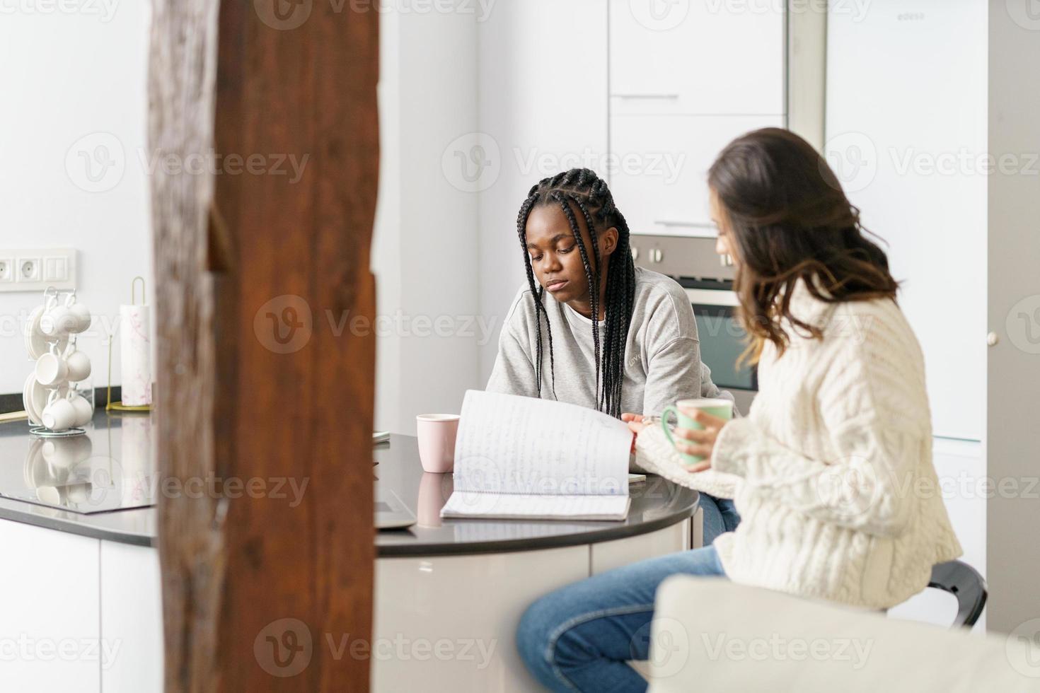 två college tjejer som studerar tillsammans hemma medan de dricker kaffe foto