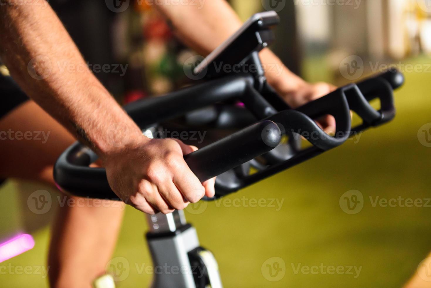 händerna på en man som tränar på ett gym som gör cykling inomhus. foto