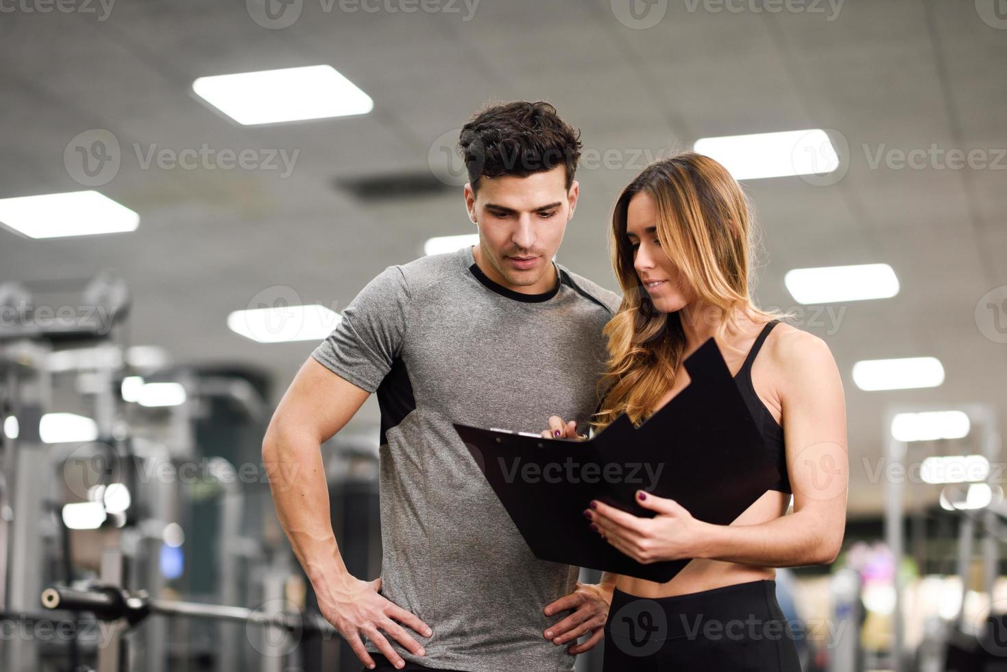 personlig tränare och klient tittar på hans framsteg på gymmet foto