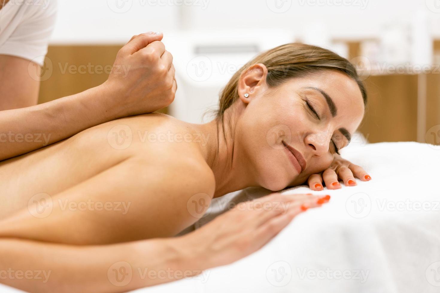medelålders kvinna som har en ryggmassage i en skönhetssalong. foto