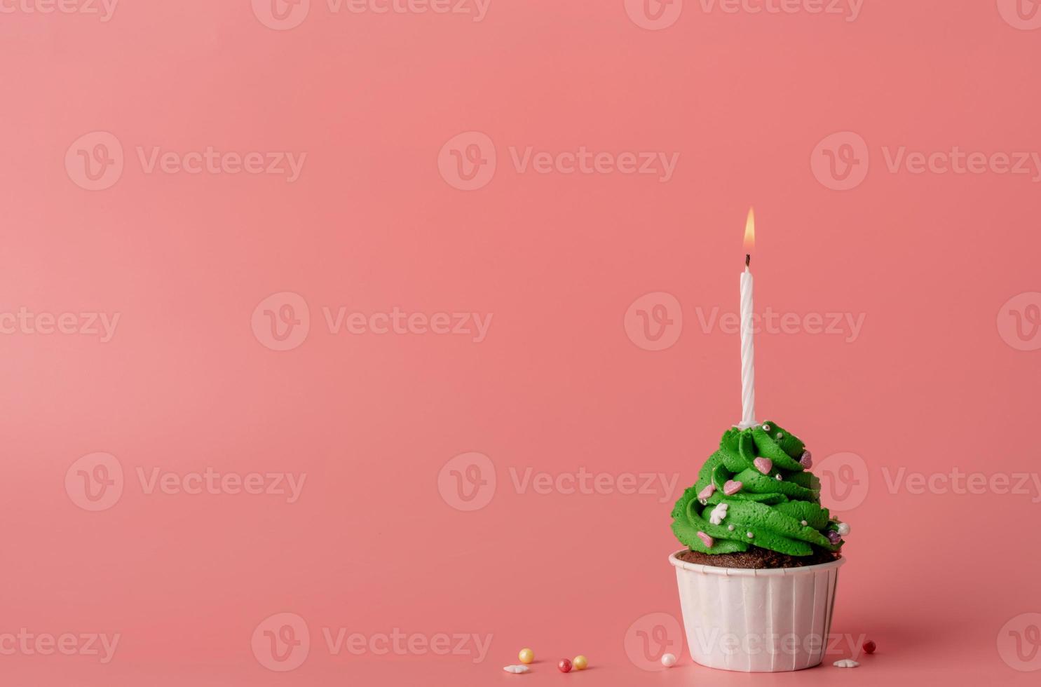 julgran formad cupcake med ett ljus på rosa bakgrund foto