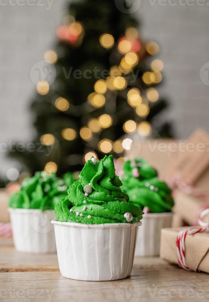 julgransformade cupcakes, omgivna av festliga dekorationer och ljus i bakgrunden foto