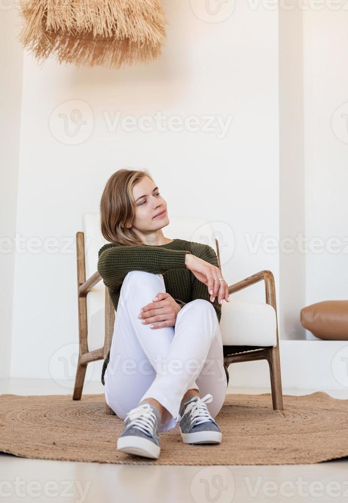 attraktiv ung kvinna sitter på stolen i ljus och luftig interiör foto