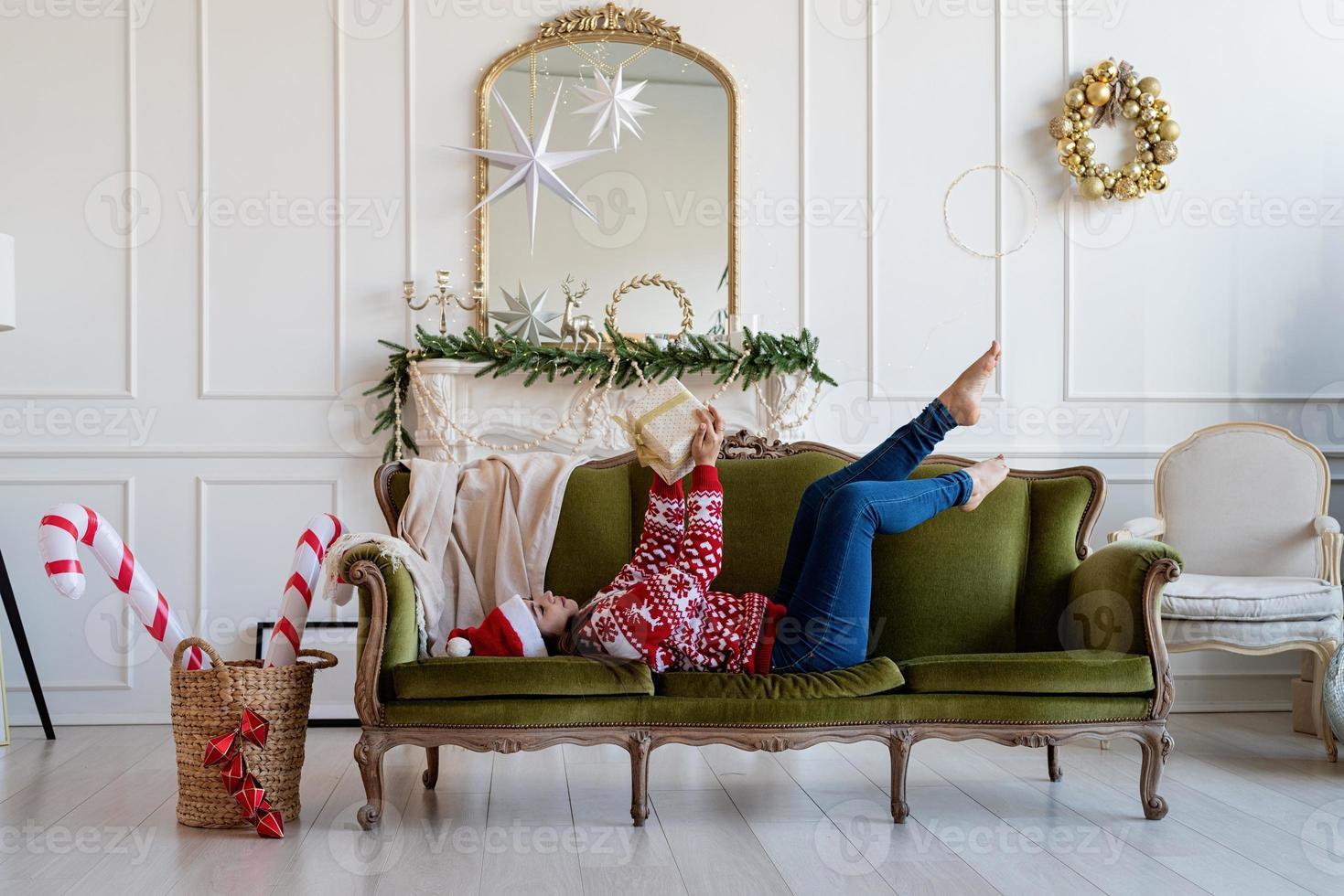 ung kvinna liggande på soffan ensam i ett dekorerat för jul vardagsrum foto