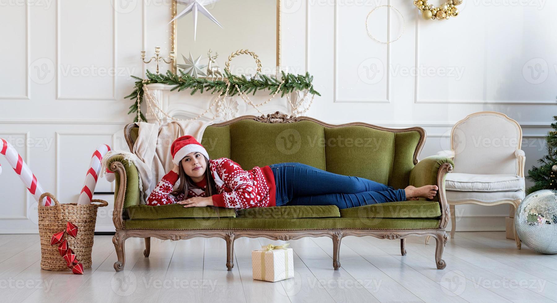 ung kvinna liggande på soffan ensam i ett dekorerat för jul vardagsrum foto