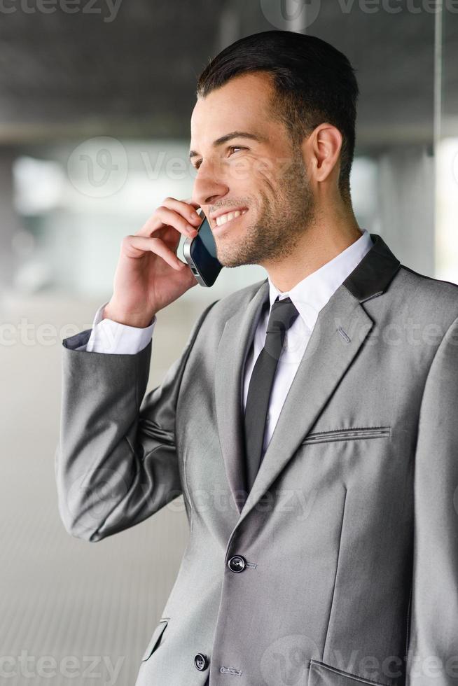 attraktiv ung affärsman i telefon i en kontorsbyggnad foto