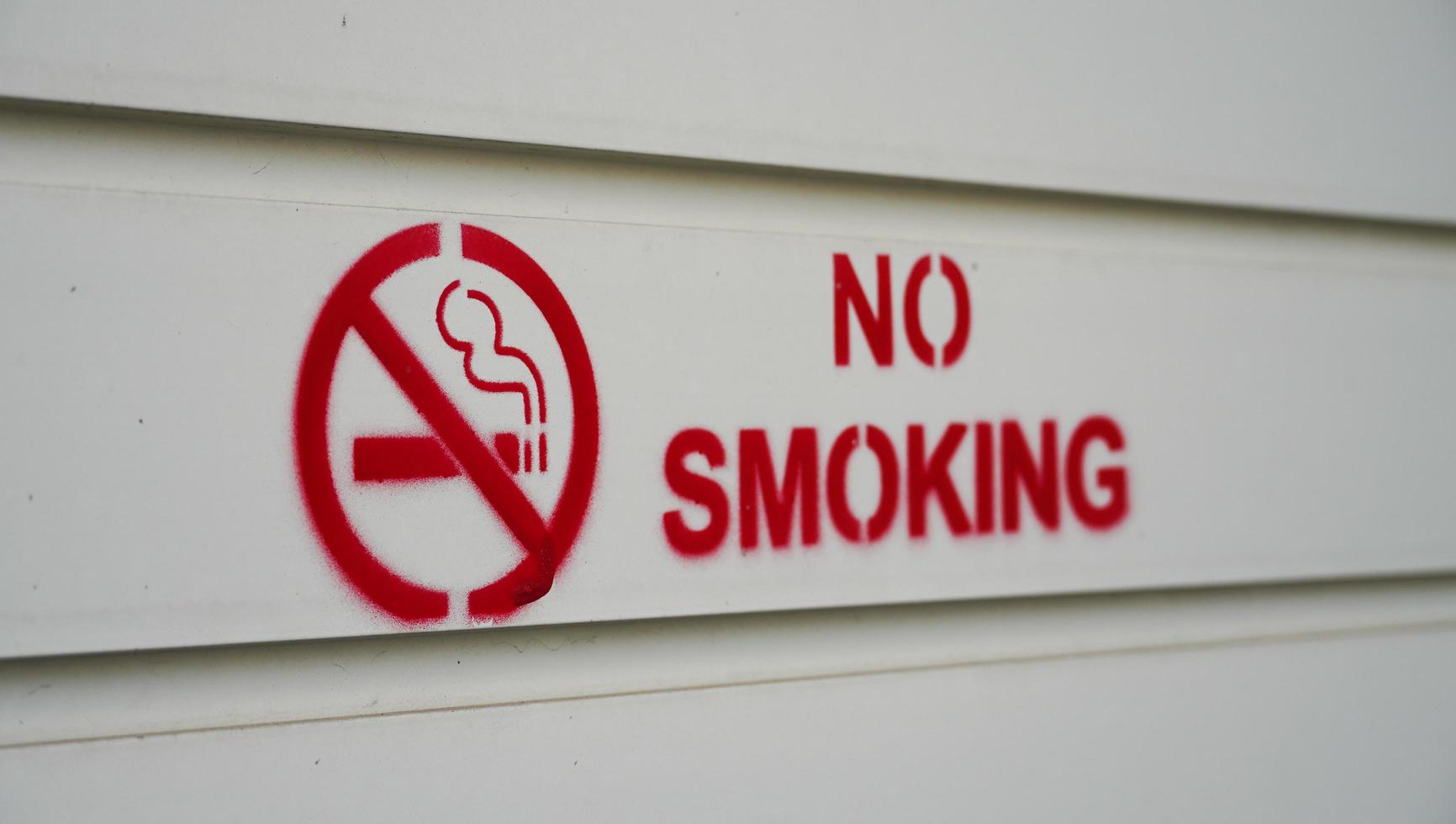 rökförbud i röd färg är tryckt på den vita väggen. försiktigheten på offentliga platser att förbjuda människor att röka i dessa områden. foto