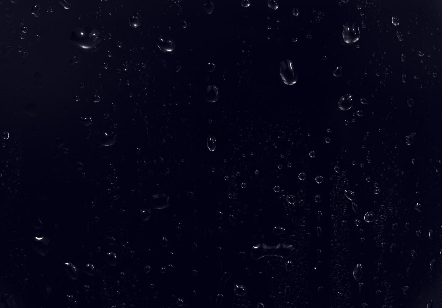 vattendroppar på svart bakgrund. abstrakta daggvattendroppar på ett fönsterglas för fotoöverlagringseffekt eller ger fräsch effekt på en mockup för drycker. makro skott av den detaljerade regndroppen. foto