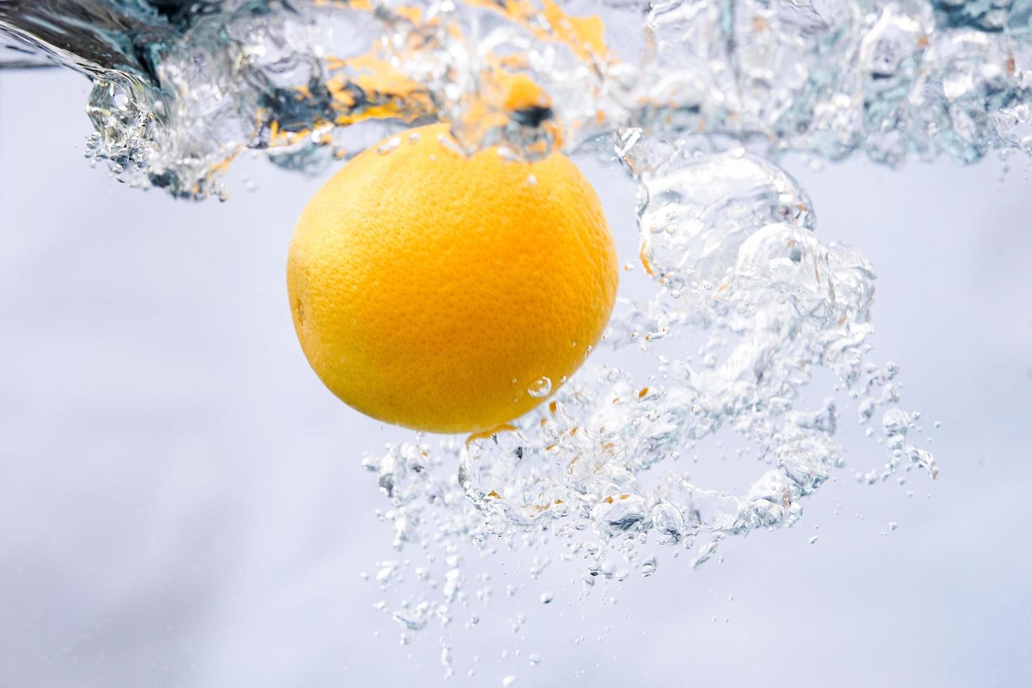 en apelsin föll i sötvatten. stänk vatten med en apelsin för en samling av frisk naturbakgrund. foto