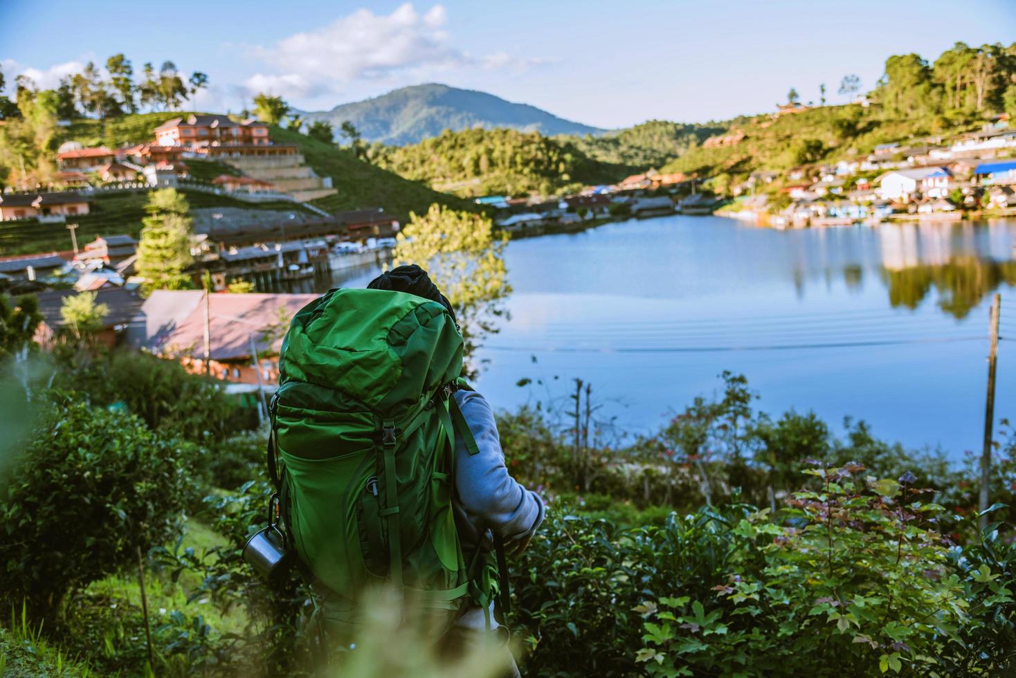 turister med ryggsäck som står i en teplantage och tittar på det vackra bergssolskenet i byn ban rak thai. foto