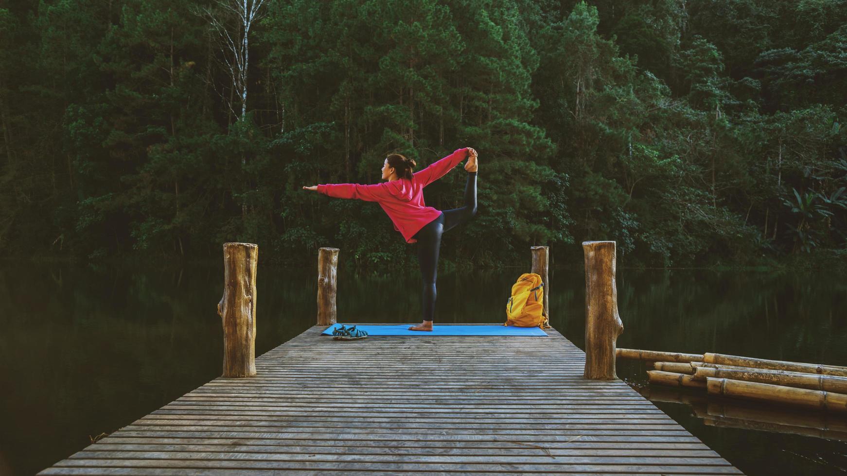 asiatiska kvinnor koppla av i semestern. spela om yoga. på berget, träna, leka yoga på bambubron bredvid sjön i dimman i pang ung, thailand. foto