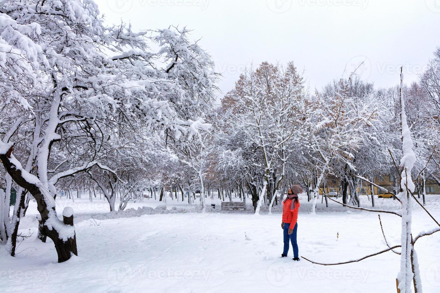 ung vacker kvinna går på vintern i en snöig fantastisk stadspark foto