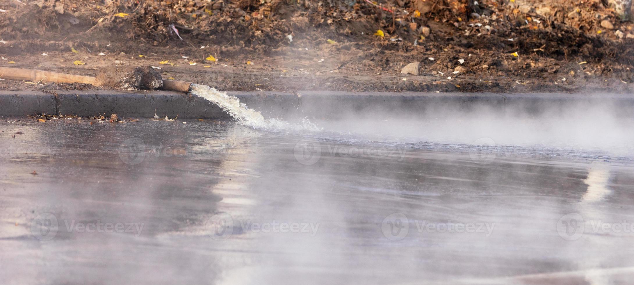 genombrottsrör med varmvatten, vatten pumpas ut på vägen med pump och brandslang, närbild. foto