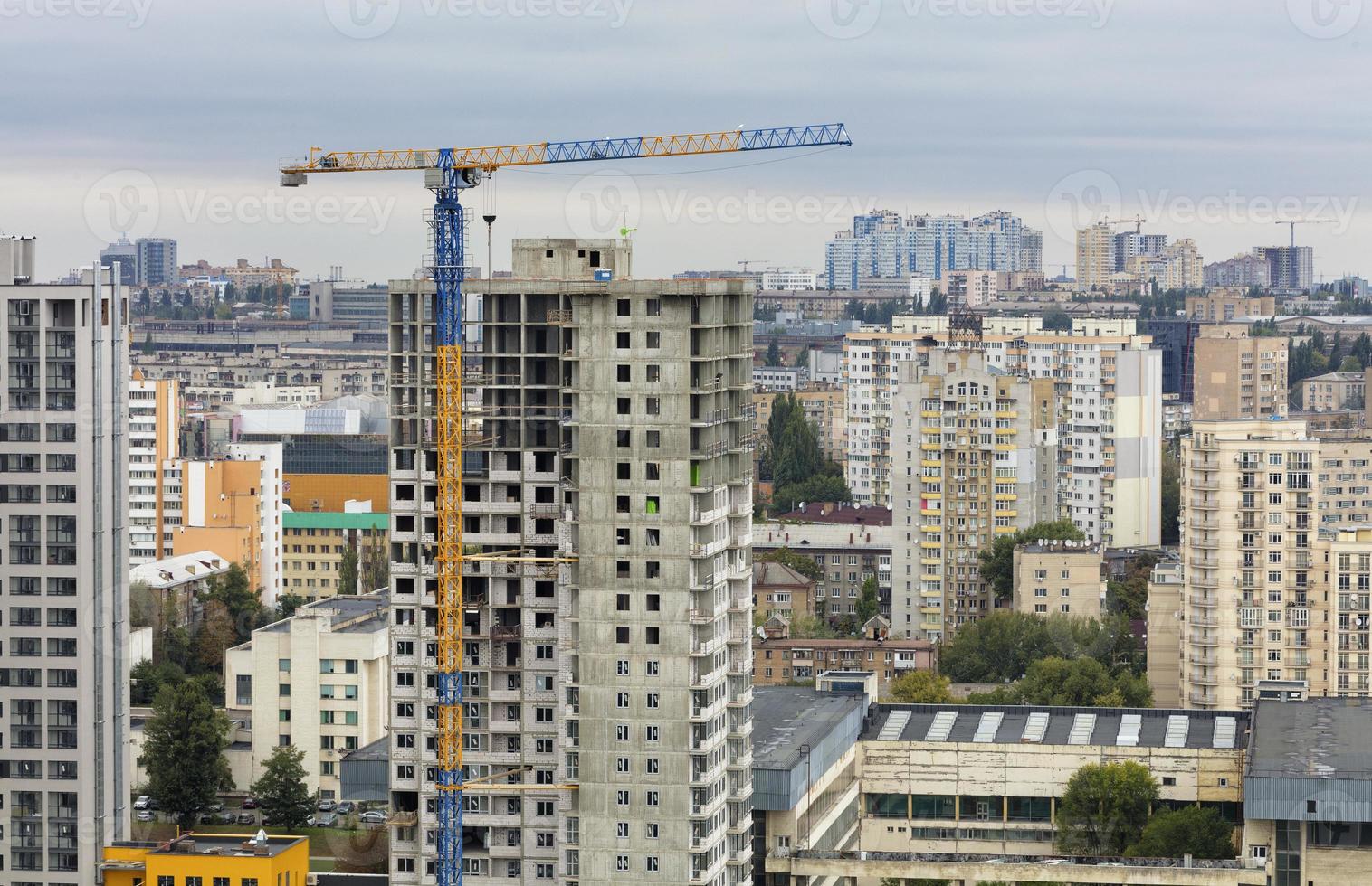 fasad och kran nära en modern betongbyggnad under uppbyggnad. foto