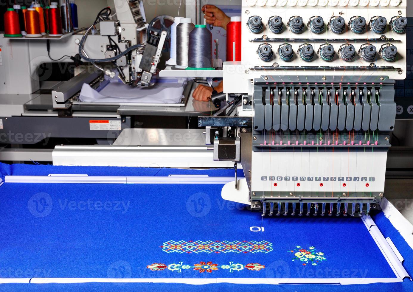 industriell broderimaskin med flerfärgade trådar på jobbet, närbild, kopieringsutrymme. foto