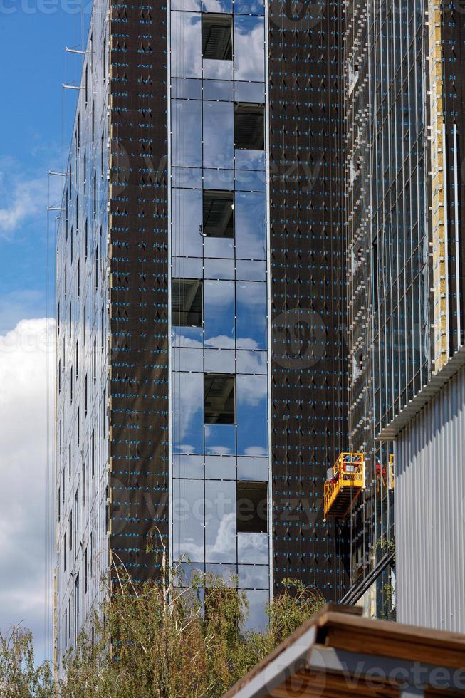 ombyggnad, fasadisolering och installation av stora fönster i ett modernt bostadshus med hjälp av en vinsch och en mobil plattform. foto