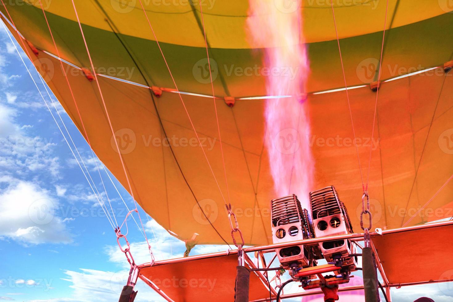 eld av korallfärg kommer ut ur en kraftfull gasfackla och fyller ballongballongen med varmluft. foto