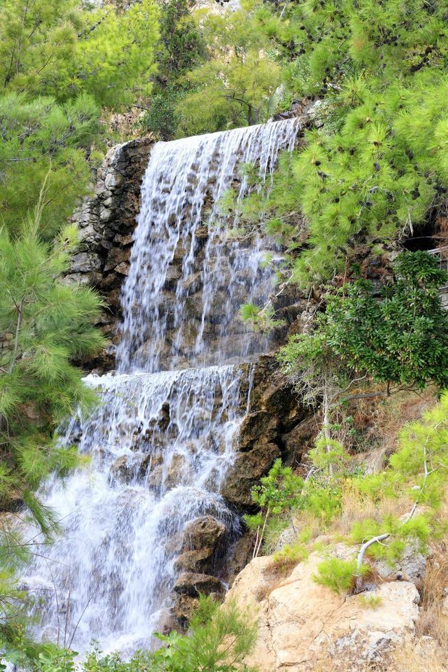 stort vattenfall med radonvatten bland stenblocken vid foten av berget i loutraki, grekland, vertikal bild. foto