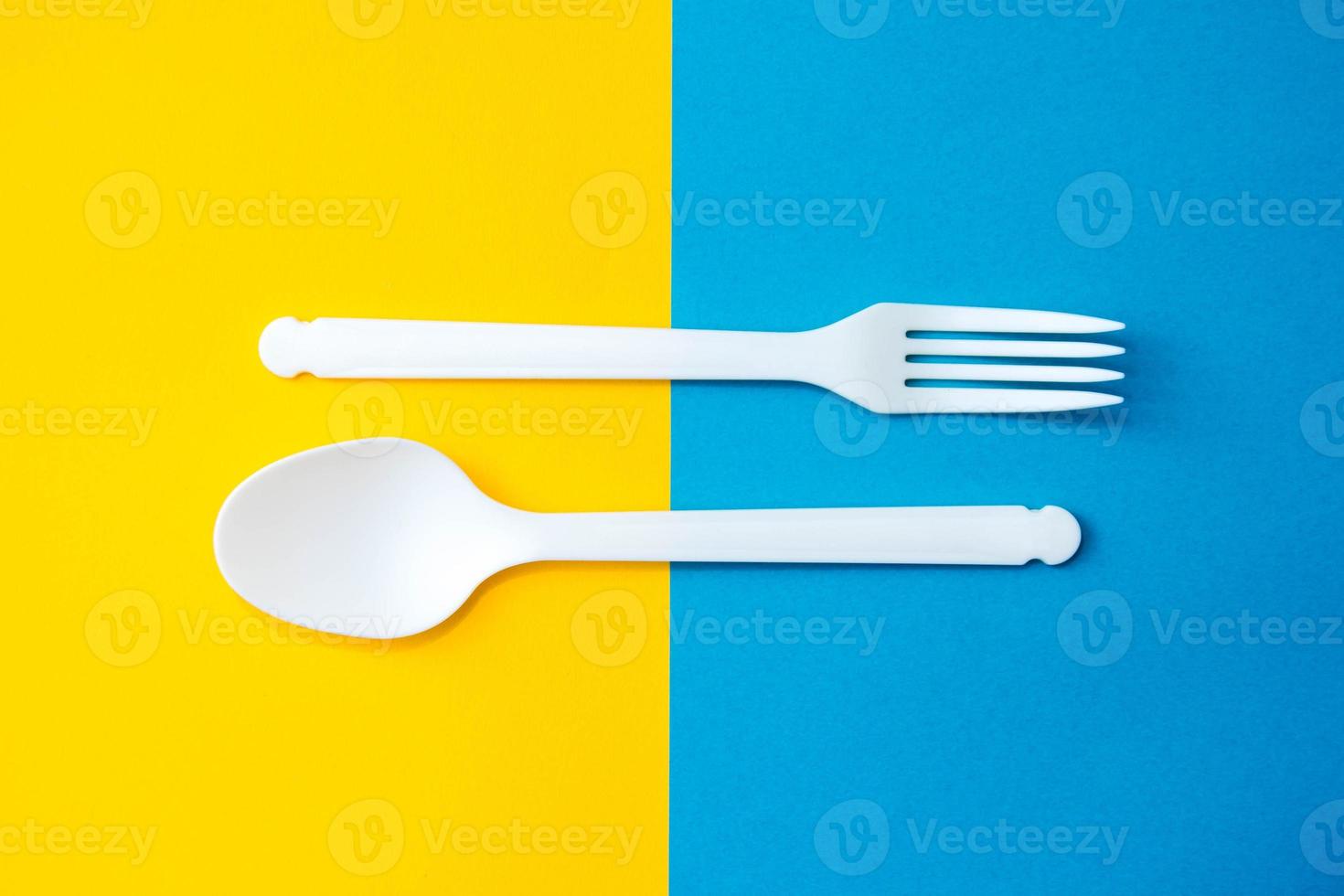 plast vit sked och gaffel på gul och blå bakgrund foto
