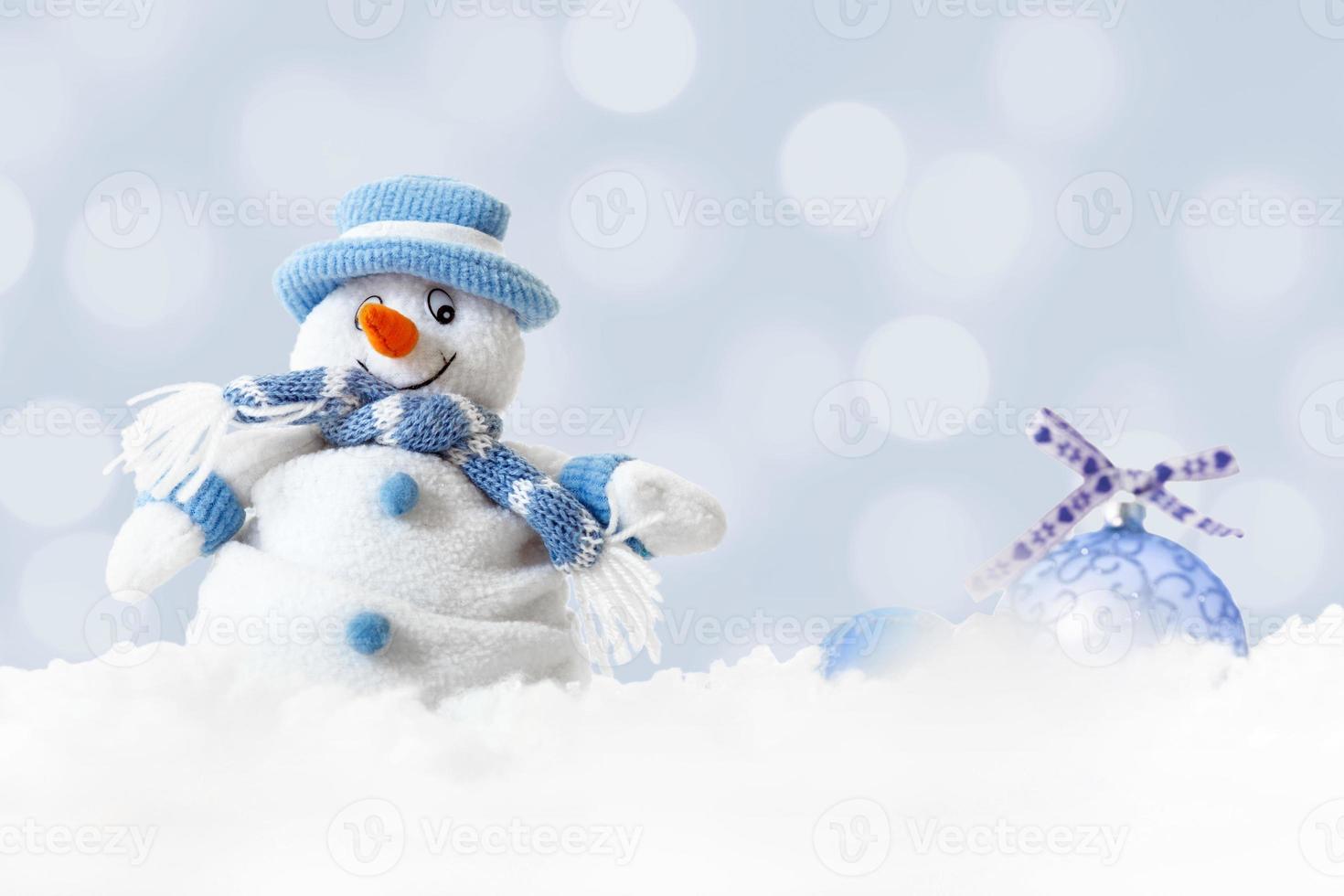 christmas glad snögubbe bär blå hatt och halsduk med xmas bollar på abstrakt ljus bakgrund foto