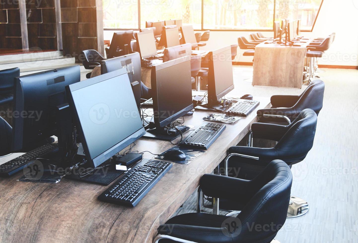 grupp av dator med bildskärm prydligt placerad i ett datorsal, datorrum på kontoret modernt med fönster foto
