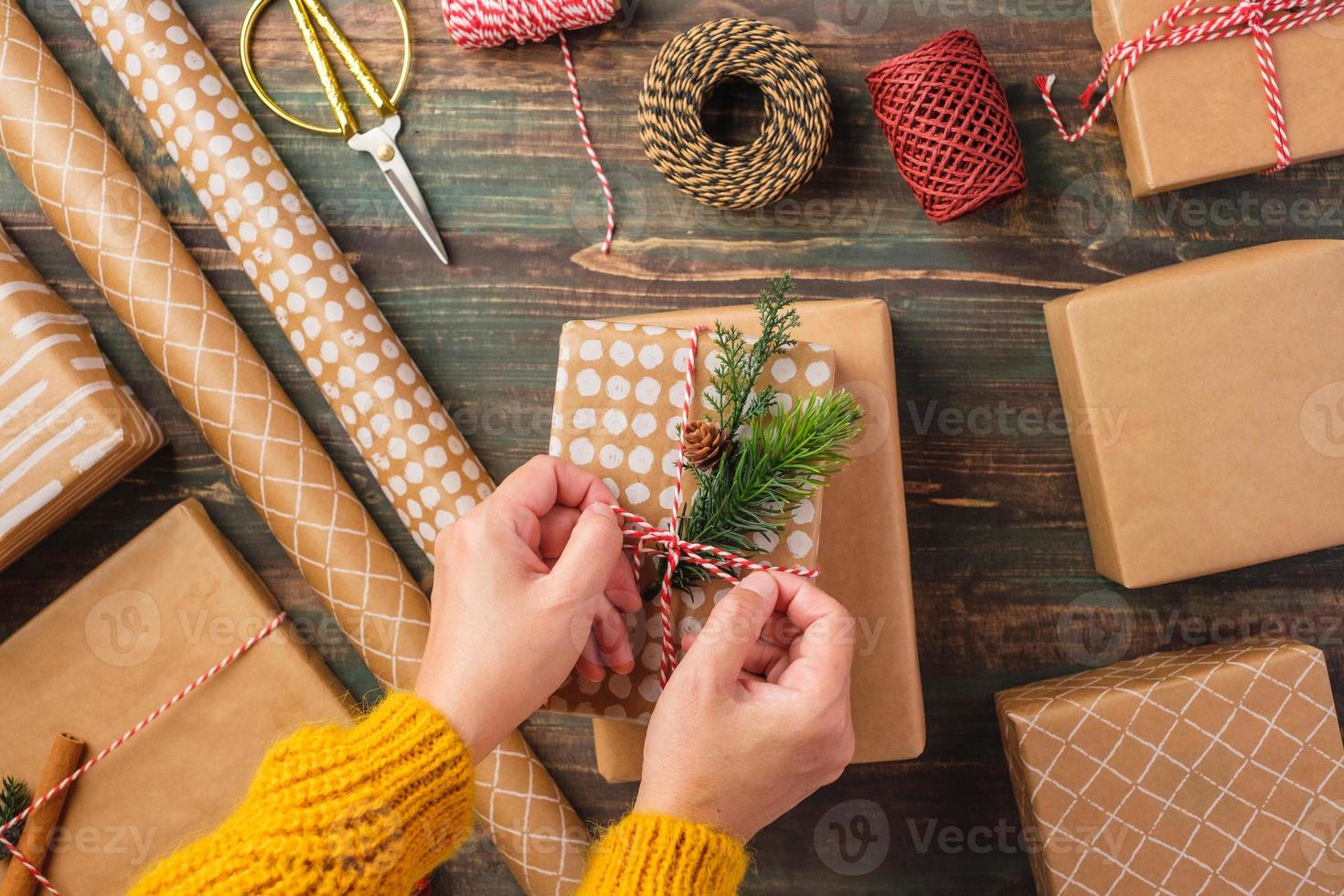 handbundet rep på julpresentförpackning med brunt pappersdekor med tallgran på träbord foto